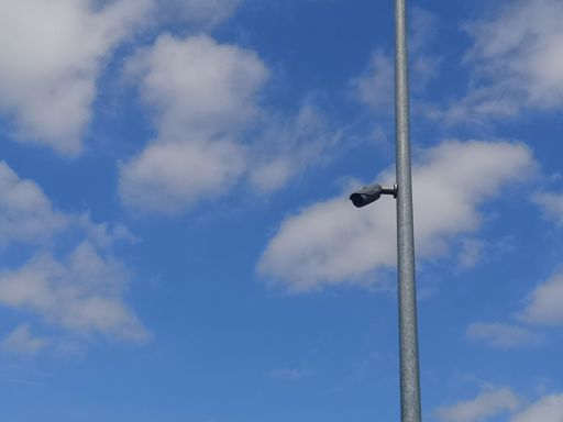 A pole video surveillance camera on a cloudy sky background