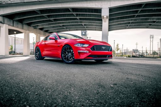 Red Ford Mustang sitting under a bridge