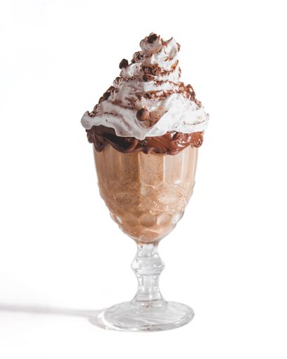 A vertical shot of a glass of chocolate milkshake with whipped cream isolated on a white background