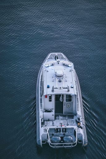 A vertical shot of a white cutter boat with a cabin floating in the waters