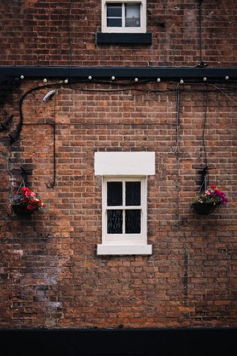 A vertical shot of a white window on an old brick wall of a house building