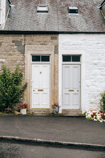 The exterior of an old house building with white wooden doors and plants growing outdoors