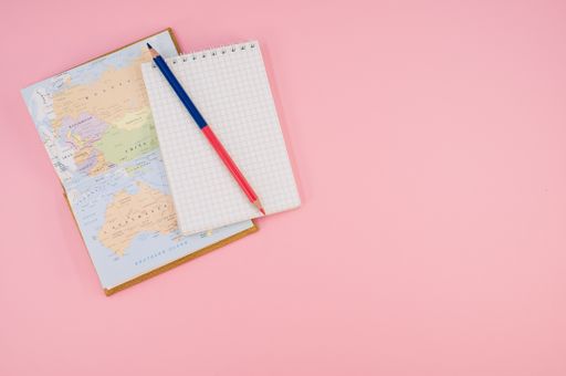 A top view of a two-sided pen and a notebook on a pink surface with text space