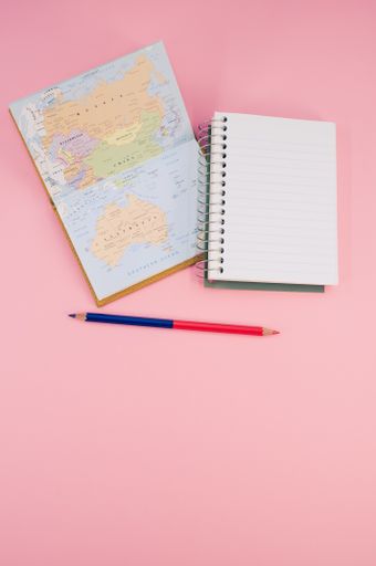 A top view of a two-sided pen and a notebook on a pink surface with text space