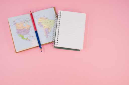 A top view of a two-sided pen and a notebook on a pink surface with text space