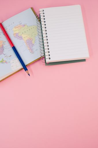 A top view of a two-sided pen and a notebook on a pink surface with text space