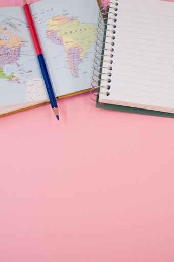 A top view of a two-sided pen and a notebook on a pink surface with text space