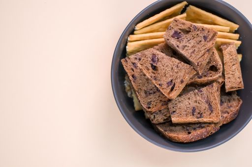 salty crackers with slices of organic brown bread in a bowl on a beige background surface