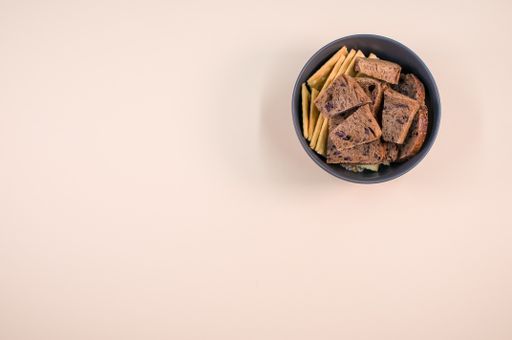 salty crackers with slices of organic brown bread in a bowl on a beige background surface
