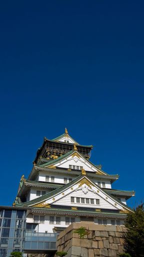 Osaka Castle under a clear blue sky, showcasing its traditional Japanese architecture and golden details.