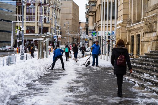 The people walking on a snowy trail while streets are being cleaned in Bucharest, Romania