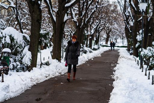 The people in warm clothes walking on a snowy trail in Bucharest, Romania