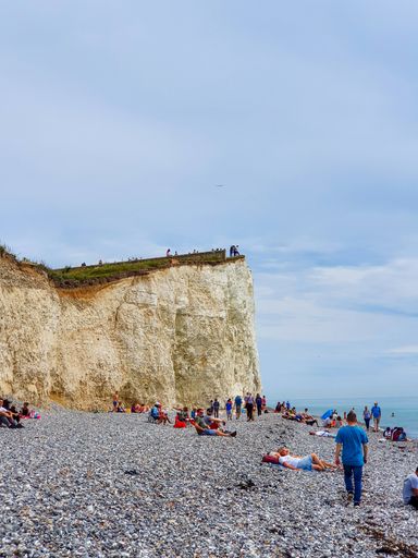 A busy summers day on the beach at Birling Gap near Beachy head as people above pose for selfies close to the cliff edge