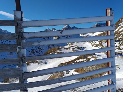 A wooden fence covered in snow behind the mountains