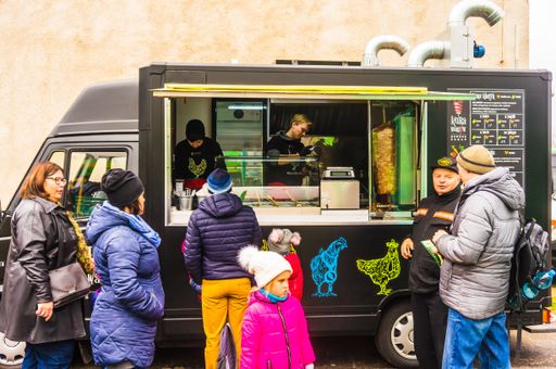A group of people ordering food by a snack stand
