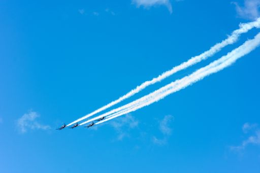 Four airplanes flying in formation with smoke trails.