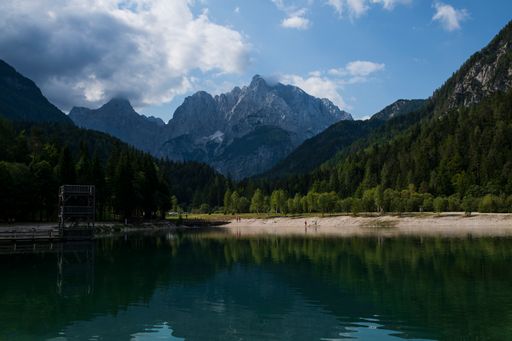 A bright summer day outdoors in the mountains with a small lake surrounded by lush greenery