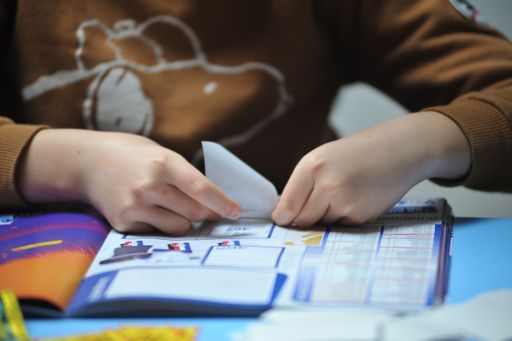 A female gluing soccer player stickers in a soccer album