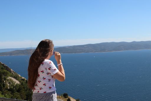 A young girl enjoying a beautiful view of an ocean on a bright sunny day