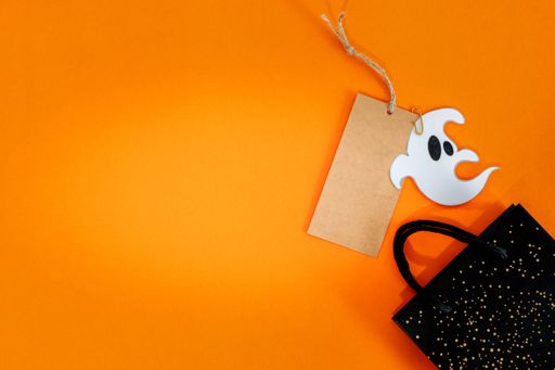 A Halloween sale banner with a label and bag on orange background