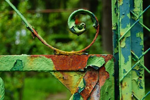 Detail of an old, rusty garden gate. Repeatedly painted over, the paint will peel off and the rust will prevail. Colourful structure.