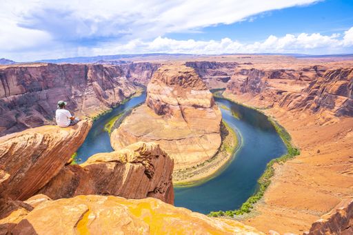A young tourist man sitting on the Horseshoe Bend, Arizona, United States