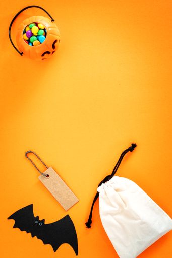 A Halloween sale banner with a label and bag on orange background