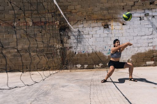 A young caucasian female playing volleyball near the net on a sunny day