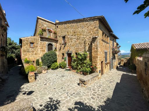 A picturesque stone building with lush green plants. Bagnoregio, Italy.