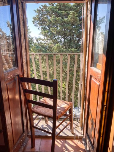 chair in sunshine on balcony against tree and blue sky