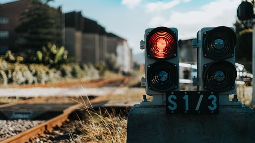 A piece of equipment shining a red light next to the train tracks