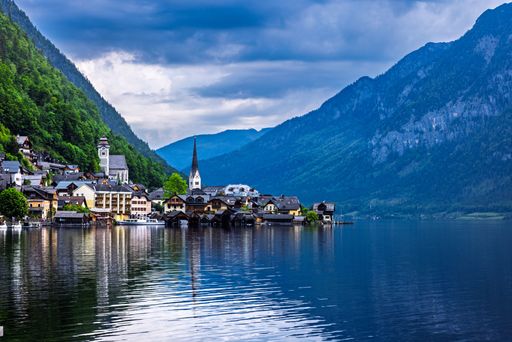 Scenic view of Hallstatt village by the lake with mountains in the background under a cloudy sky.