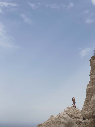 A vertical shot of two young men about to jump from a cliff in Almeria, Spain