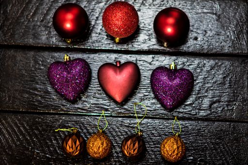A closeup shot of colorful Christmas toys of different shapes on a black wooden surface