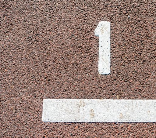 An overhead closeup shot of a number "1" painted in white on a ground