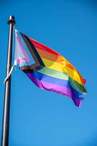 A close up of Rainbow LGBT flag fluttering on blue sky background