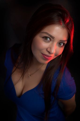 A vertical shot of a sexy young caucasian female wearing a beautiful electric blue dress and posing