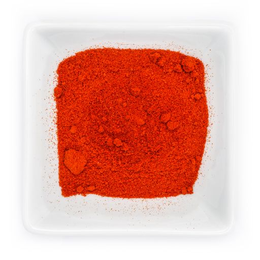 A top view of red smoked paprika powder in a white bowl