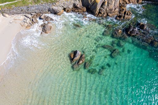 coastal landscape rocks on a sandy beach with azure turquoise sea, aerial drone top view