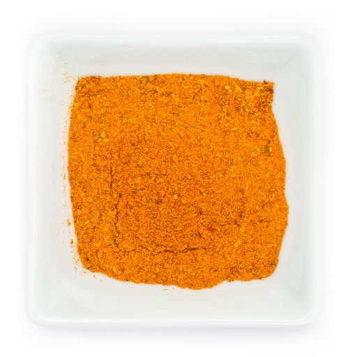 A top view of orange spicy curry powder in a white bowl