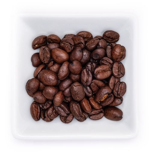 A top view of dark brown coffee beans in a white bowl