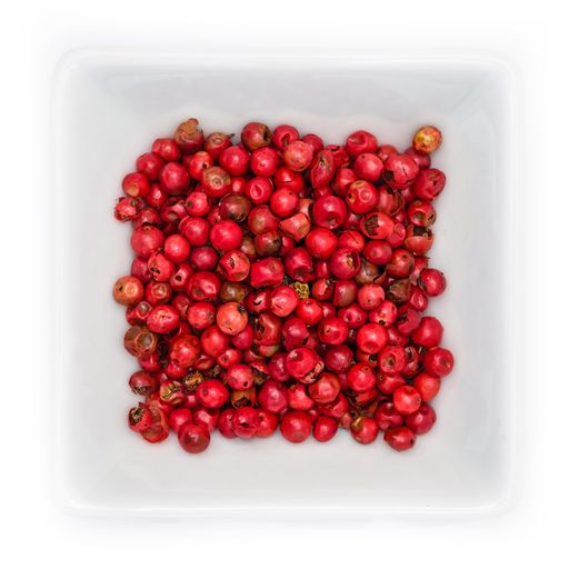 A top view of red peppercorns spice in a white bowl