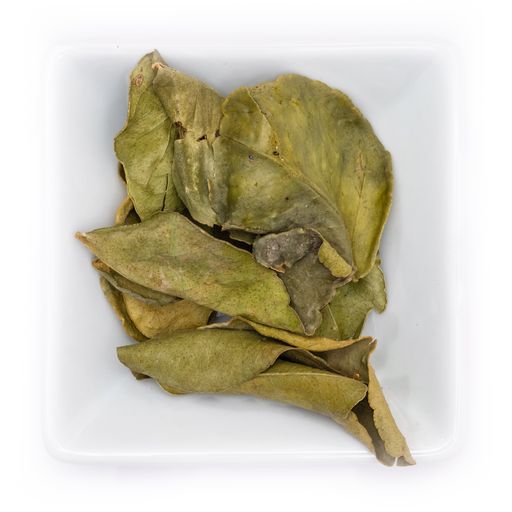 A top view of dried kaffir lime leaves spice in a white bowl