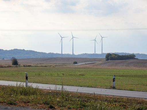 The wind turbines in the field with dense vegetation against a cloudy sky