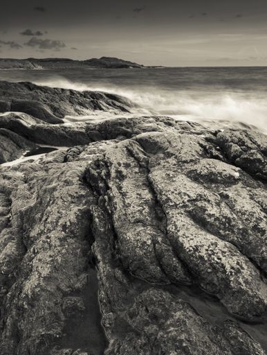 A vertical greyscale surrounded by the wavy sea under the sunlight at daytime