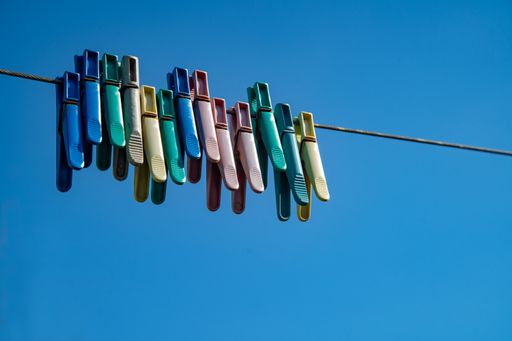Multicolored clothespins on a rope against the blue sky