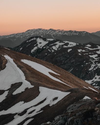 A vertical shot of a beautiful mountainous area covered with snow during the sunset