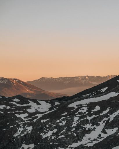 A vertical shot of a beautiful mountainous area covered with snow during the sunset