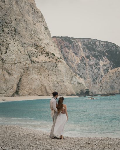 A young couple hugging on the shore and enjoying the view of a cliff