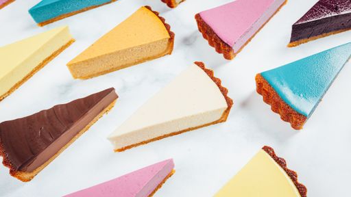 Different color vegan cakes cut in a triangle shape on a white background